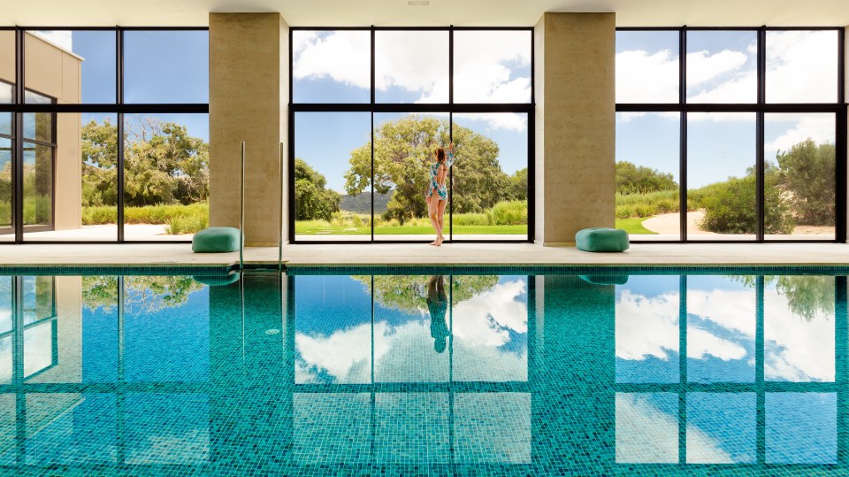 There is a tranquil spa with an indoor pool overlooking another terrace with a large outdoor pool and cushioned day beds