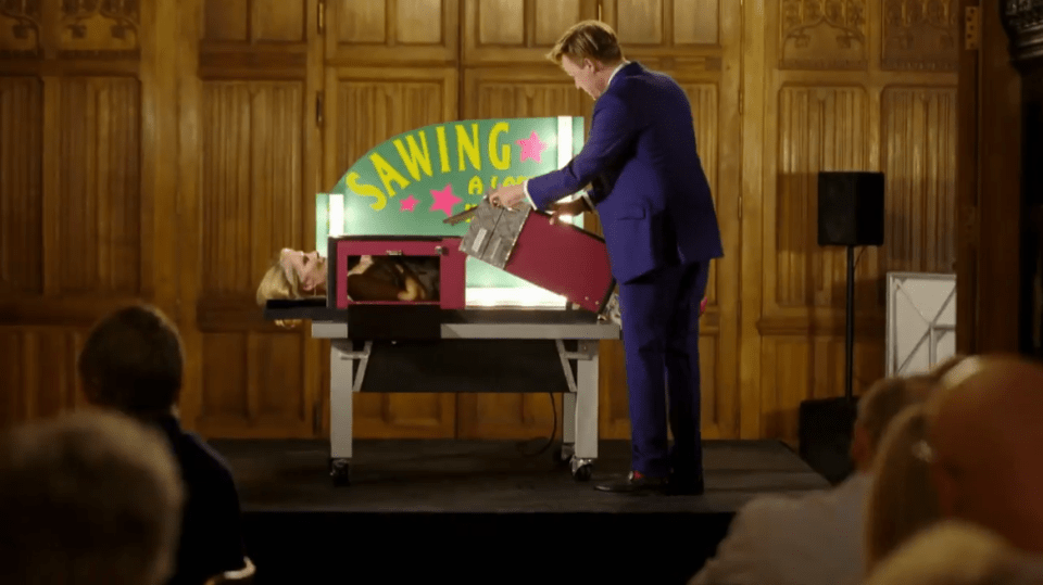 Diners are entertained by a magician sawing a woman in half