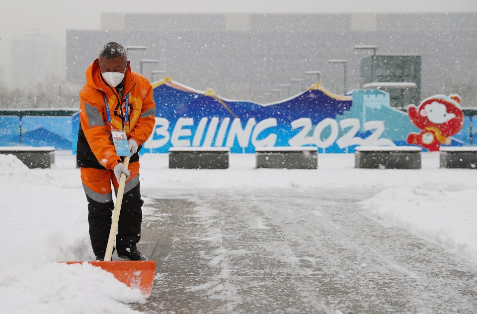 A volunteer clears a pathway at the Main Medi on day 9 of the Games