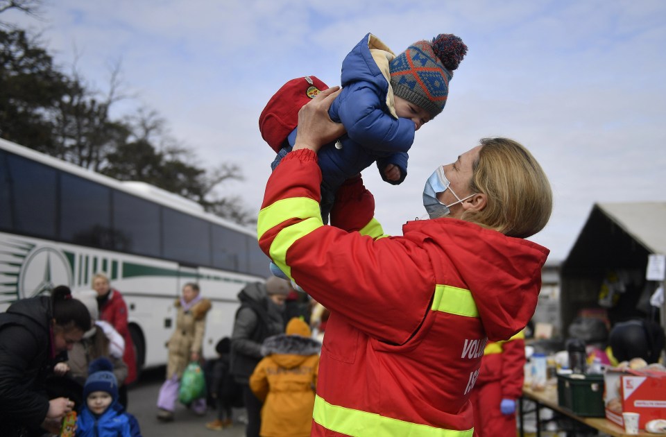 A volunteer takes care of a child as thousands of Ukrainian women and children cross the border into Romania