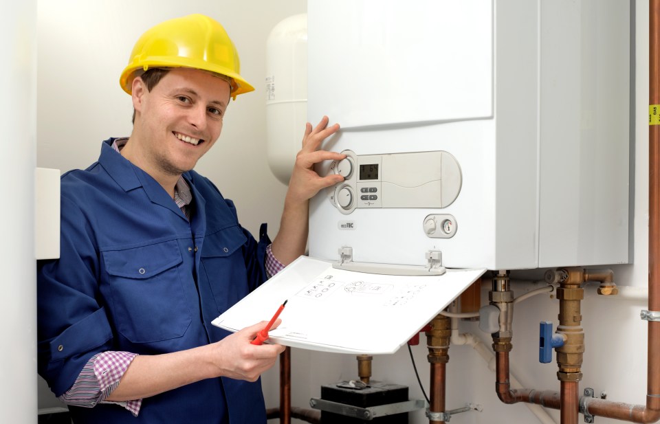 a man wearing a hard hat is working on a boiler