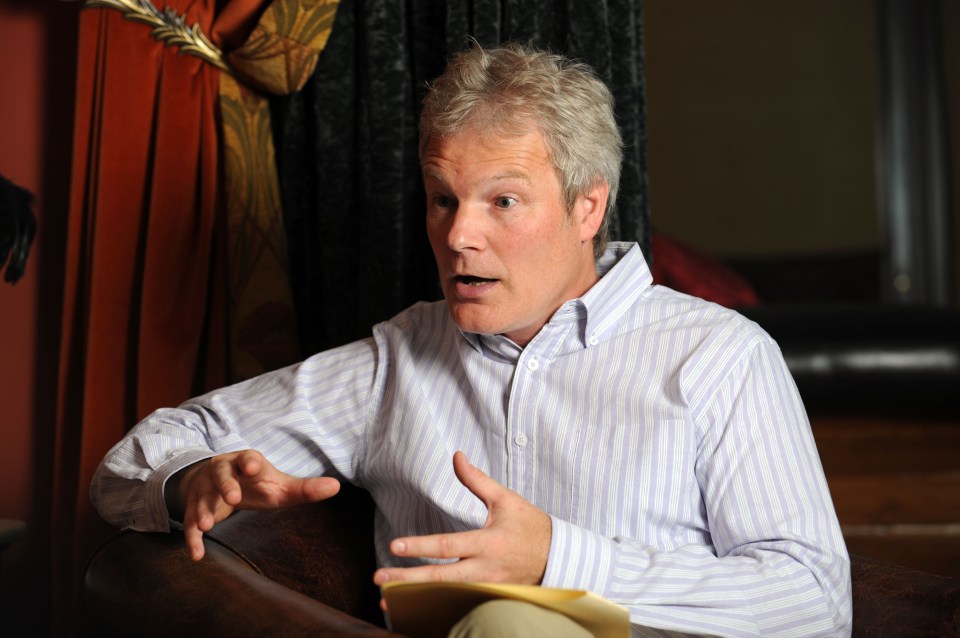 a man in a striped shirt is talking with his hands outstretched