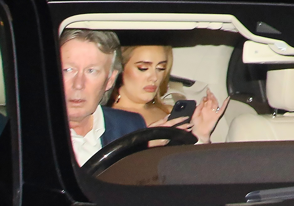 Adele checks her phone as she's driven away from the Brits