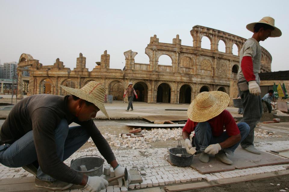 Workers build a pavement outside a replica of the Roman Colosseum in Macau