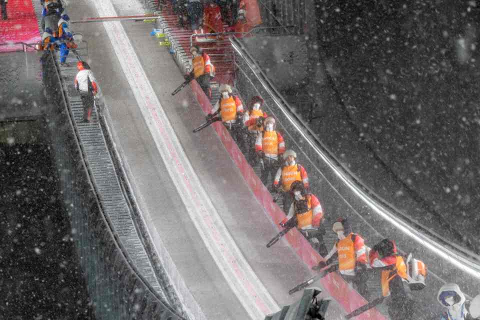 Ground staff wiped off snow at the in-run for training for the Ski Jumping Men's Large Hill at the Zhangjiakou National Ski Jumping Centre