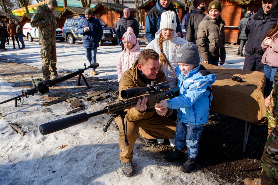 A Ukrainian boy is shown how to use a rifle