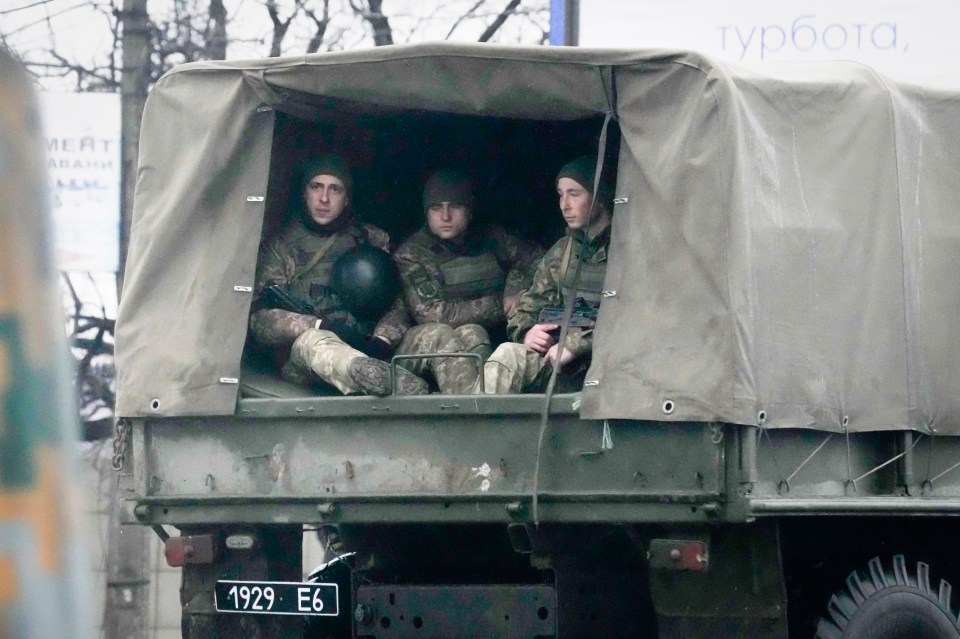 Ukrainian soldiers ride in a military vehicle in Mariupol