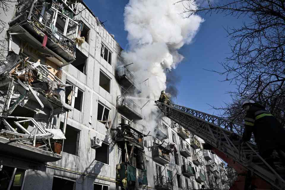 Firefighters hose down apartments after a rocket strike today in Chuguiv