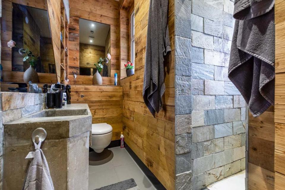 The toilet maintains the industrial cabin effect with a stone and wood interior