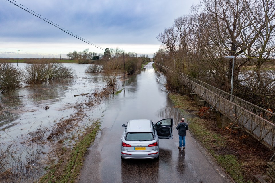 A motorist was seen wondering what to do next after the River Delph in Sutton Gault, Cambridgeshire burst its banks