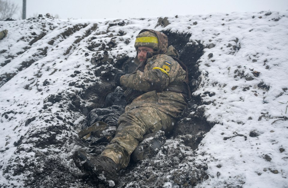 A Ukrainian serviceman lies on the ground at a fighting position in Kharkiv