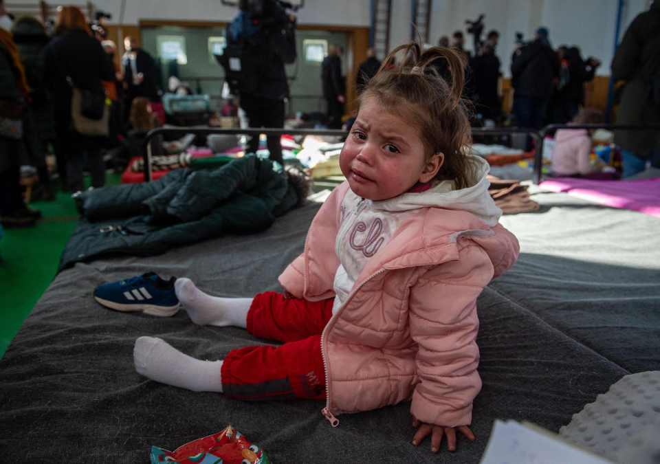 A girl cries as she sits on a camp bed at a temporary shelter for Ukrainian refugees at the border crossing in Ubla, eastern Slovakia