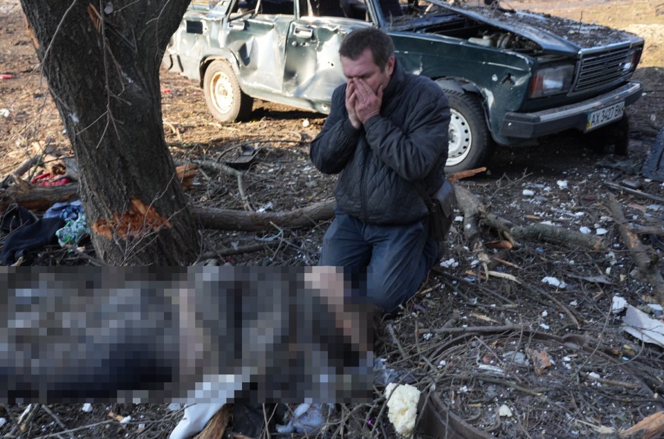 A man can be seen crying over a loved one's body after a strike in Kharkiv