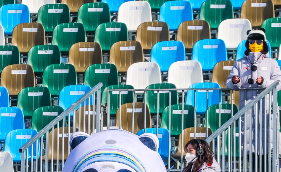 Officials and a giant panda watching one event with empty seats behind