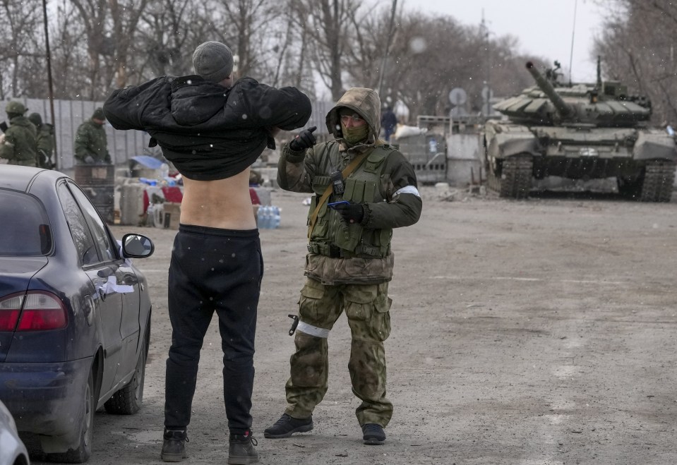 A civilian at a checkpoint is searched by a pro-Russian separatist in Mariupol