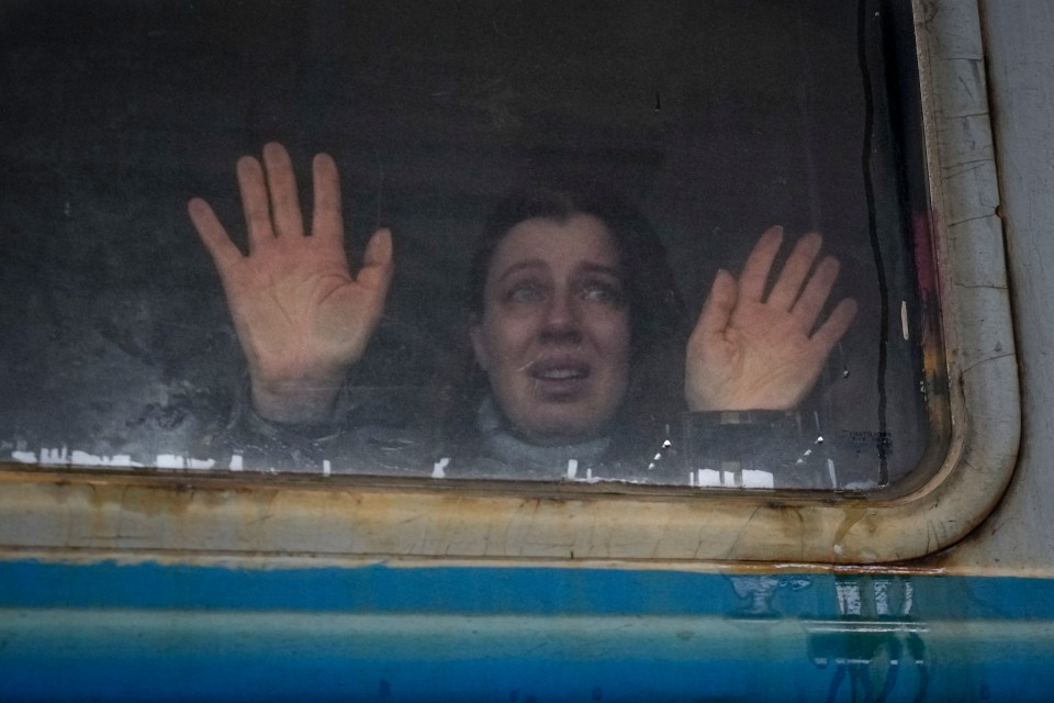 A sobbing woman waves goodbye to her relatives as she leaves Kyiv station