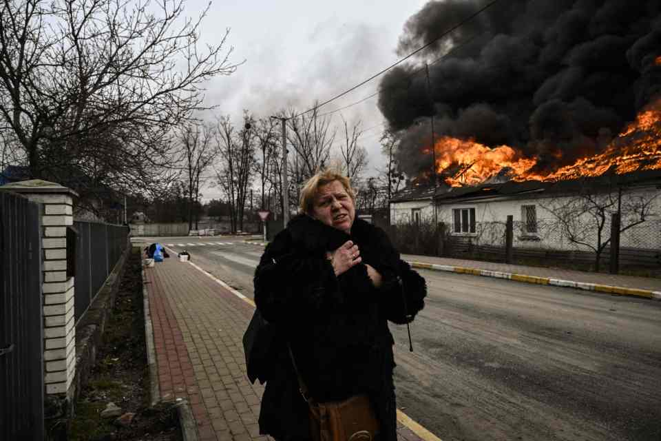 A woman reacts as she stands in front of a house burning after being shelled in the city of Irpin, outside Kyiv