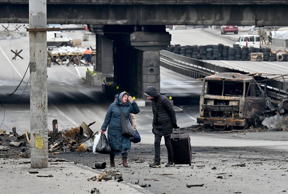 A woman flees with her belongings through the debris of a battle in Kyiv