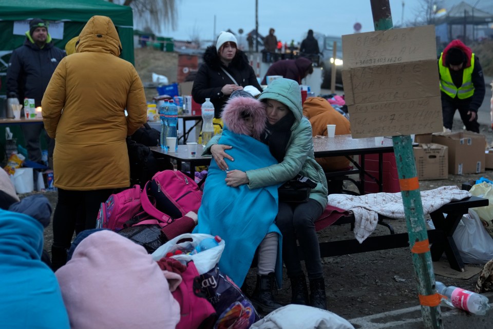 A mother embraces her daughter as they rest at the border crossing in Medyka, Poland