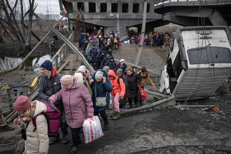 Civilians fleeing across a blown-up bridge on the outskirts of Kyiv