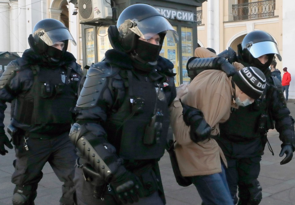 Russian policemen detain a protestor in anti-war demonstrations in St Petersburg