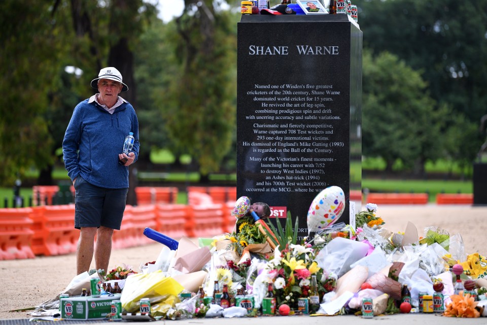 A mourner observes tributes to Warne at his statue outside the MCG in Melbourne