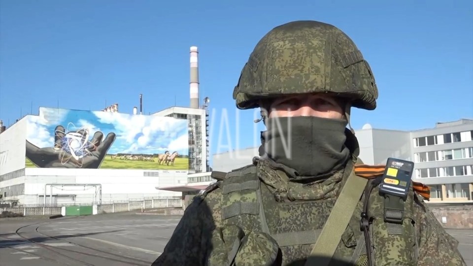 A Russian soldier poses in front of the decommissioned Chernobyl nuclear plant