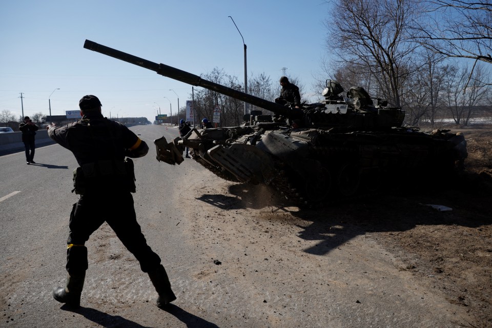 Ukrainian servicemen drive off in a Russian tank they captured near Kyiv