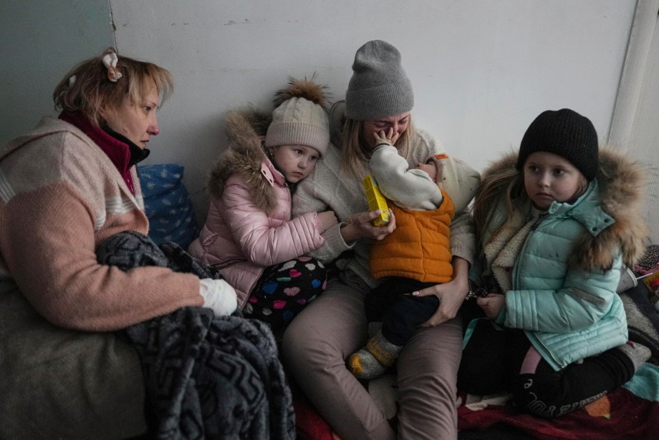 Women and children sit on the floor of a corridor in a hospital in Mariupol, eastern Ukraine