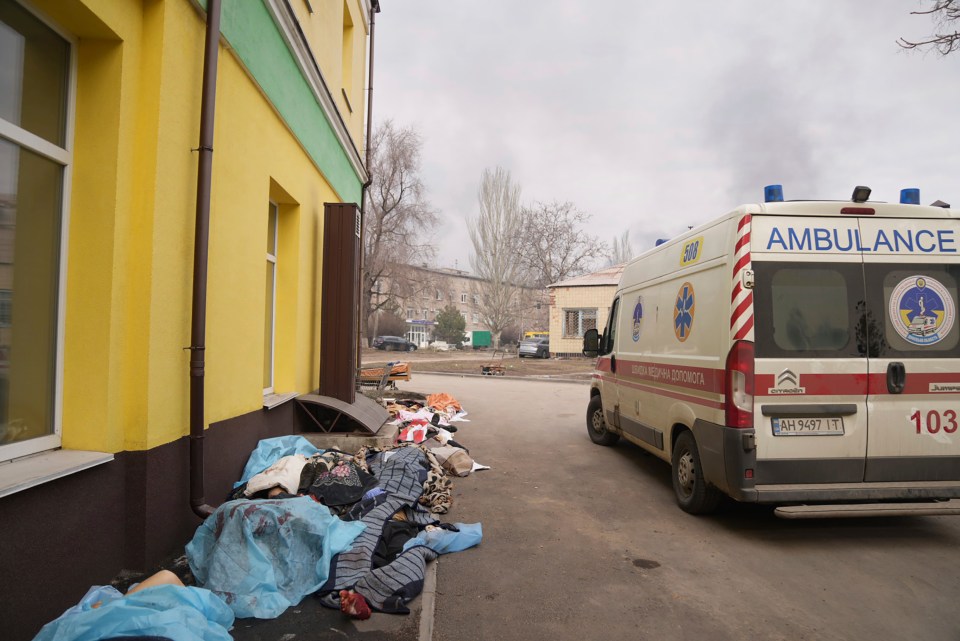 Bodies of people killed by shelling lay covered outside a hospital in Mariupol