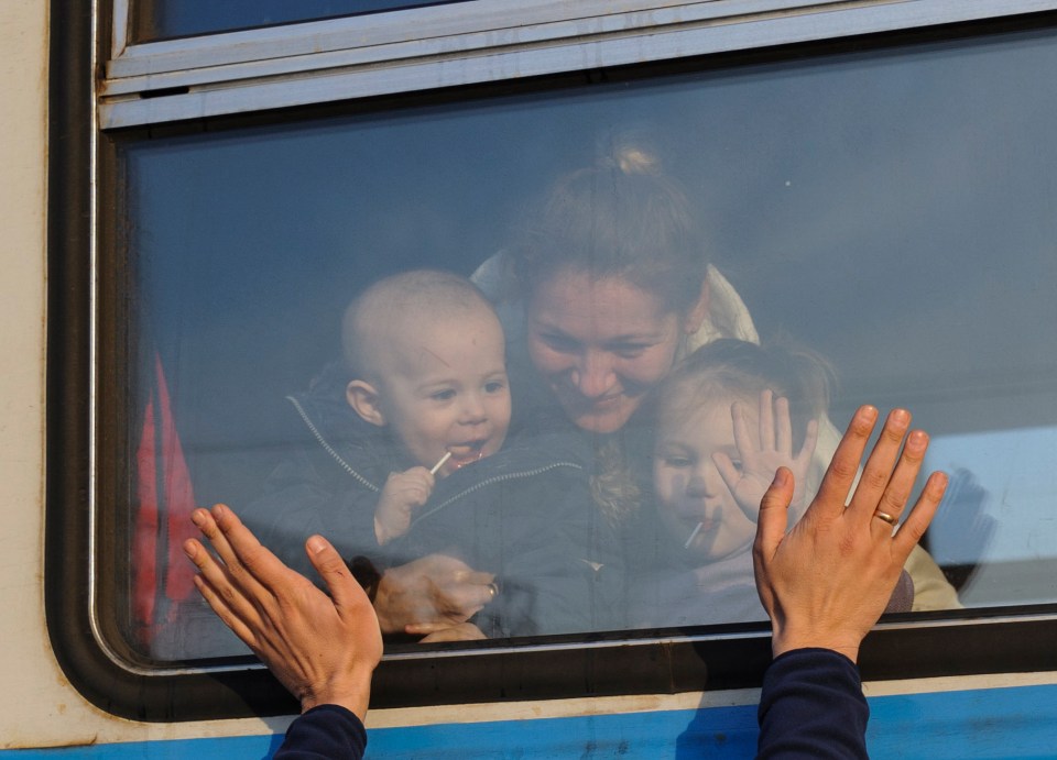 Ukrainian refugees wave goodbye as they prepare to depart to Poland