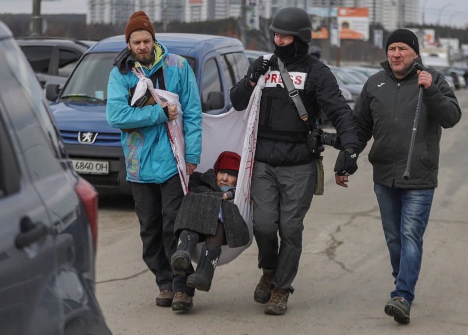 Residents and journalist help an elderly woman to flee from the frontline town of Irpin,  next to Kyiv