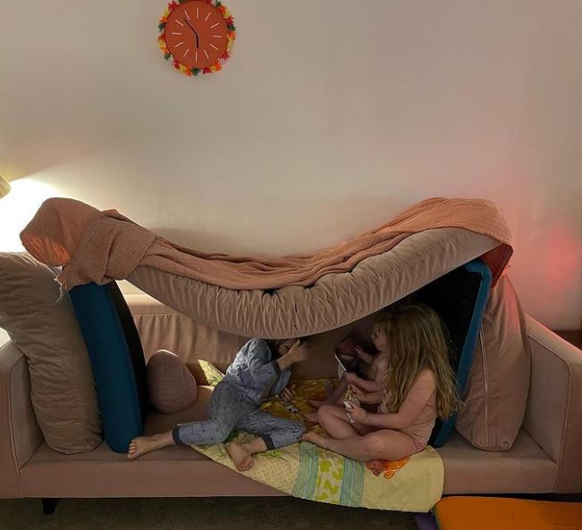 The living room has a large velvet sofa