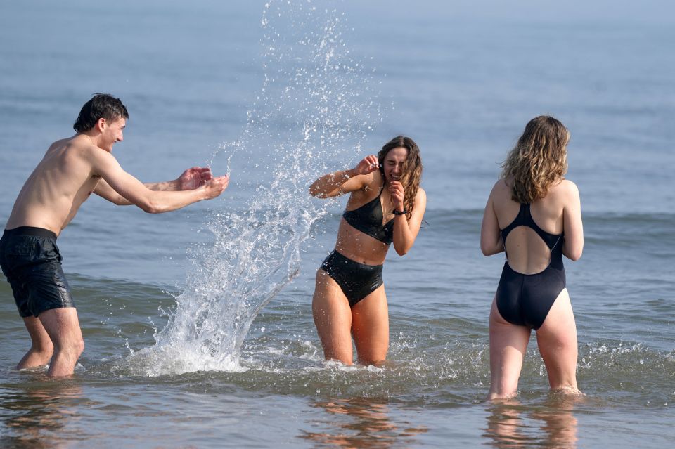 Beachgoers make a splash in the sea on Tynemouth Beach, Tyne and Wear