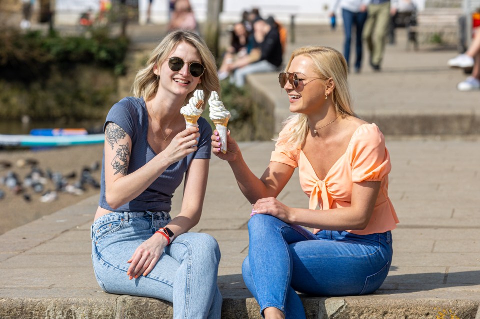 Two pals cool off with an ice cream as they enjoy the sunshine along the River Thames