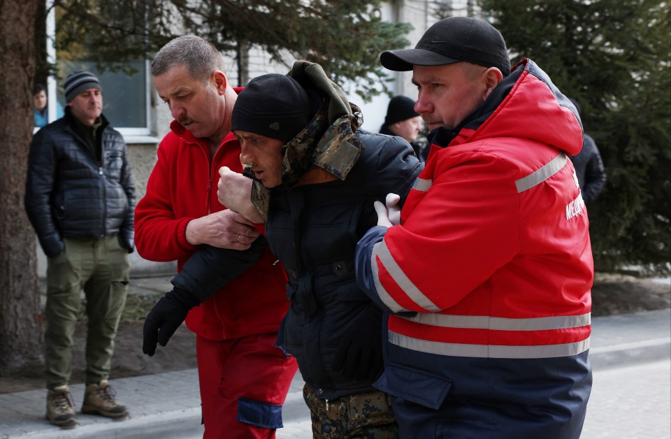 A patient is assisted by medical staff as he arrives at Novoiavorivsk District Hospital following a strike at the nearby military complex