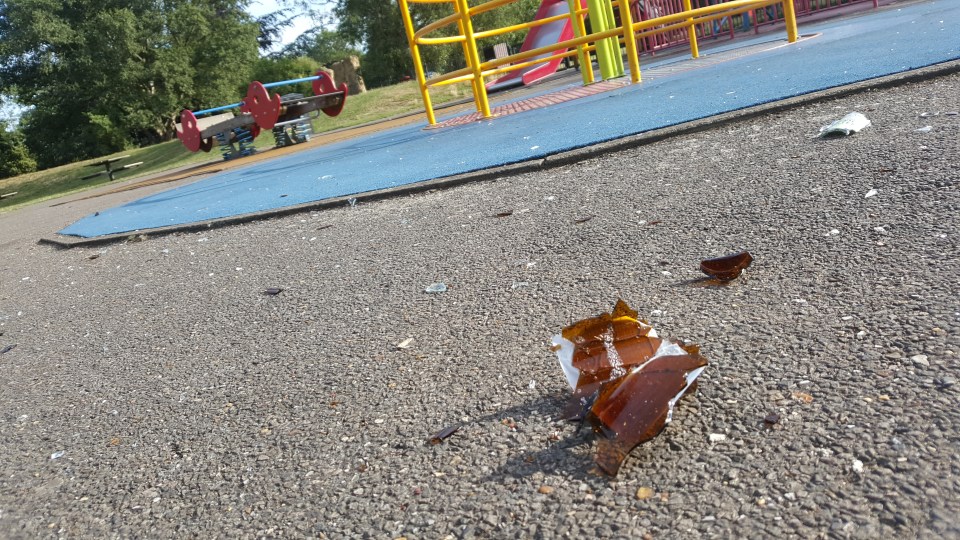 Smashed glass scattered across the ground in the play area