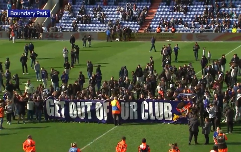 Oldham fans stormed the pitch with a banner that read ‘Get out of our club’