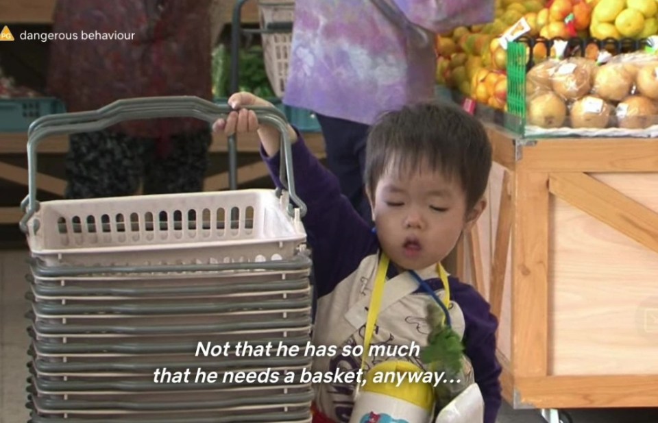 The little lad struggles to lift a basket