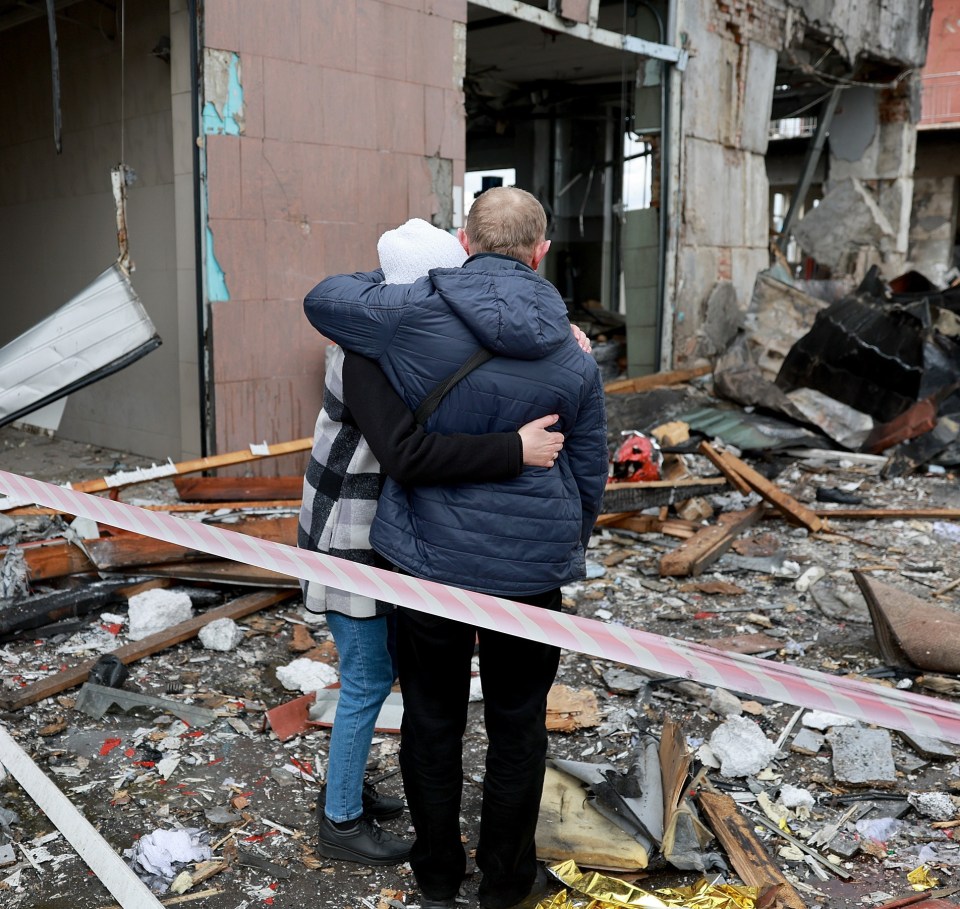 Two people hug as they look on at the destruction caused when a civilian building was hit by a Russian missile in Lviv