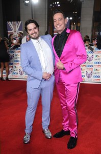 two men in suits pose on a red carpet sponsored by itv