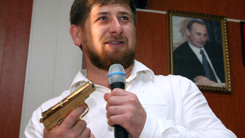 Ramzan Kadyrov pictured with a golden pistol - and a portrait of Vladimir Putin