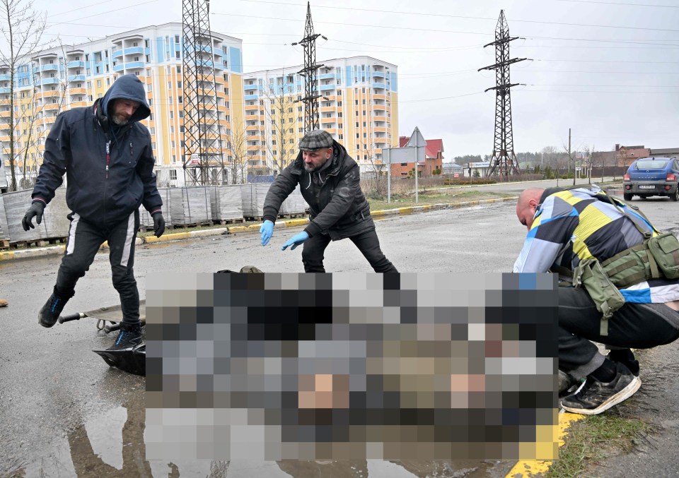 Communal workers collect the bodies of two men killed during Russian army shelling of the town of Bucha