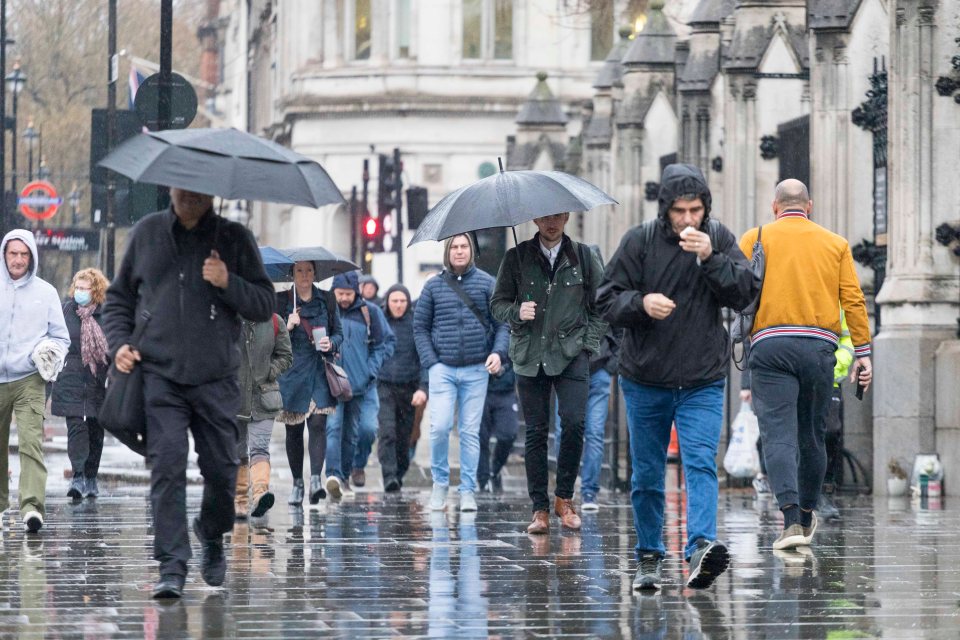 Shoppers squeezed together under an umbrella to shelter from the rain in Manchester