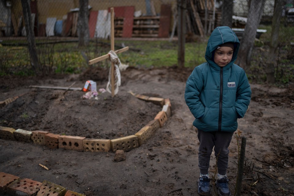 Little Vlad Tanyuk, six, stands next to the grave of his mum near Kyiv