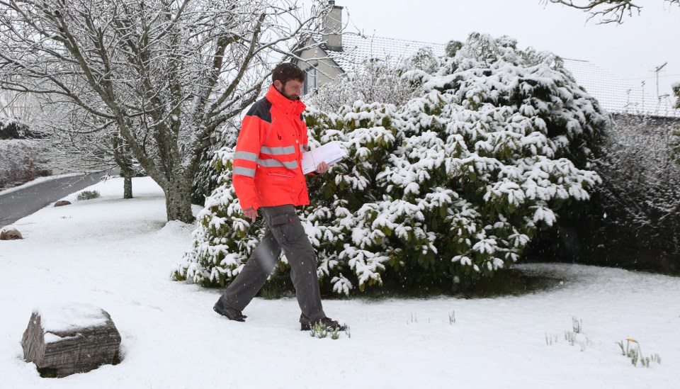 A postie delivers the mail in snow this morning in the village of Culbokie near Inverness