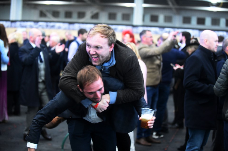 A suited and booted man celebrated what appeared to be a big win by leaping on his friend's back