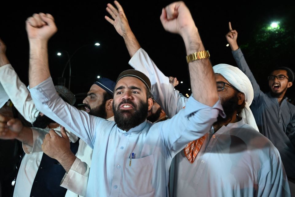 Opposition party supporters chant slogans against Khan outside the parliament house building