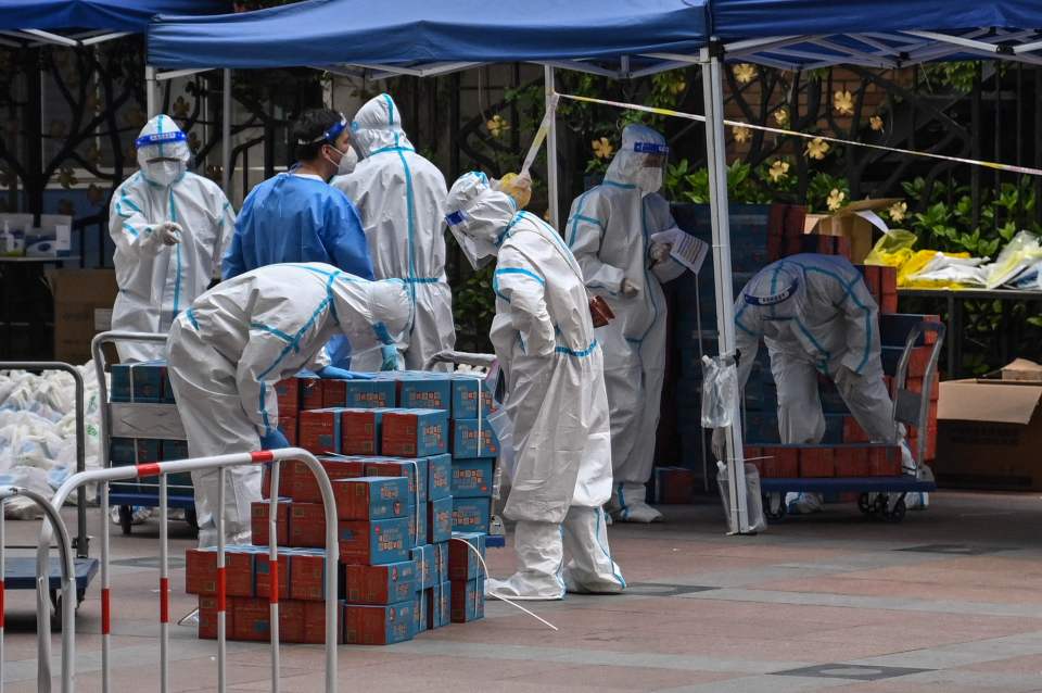 Workers wearing PPE are seen next to food delivered by the local government for residents