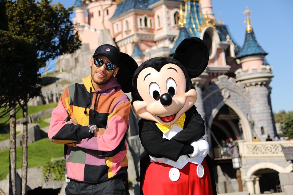 Neymar Jr. posing with Mickey in front of Sleeping Beauty Castle